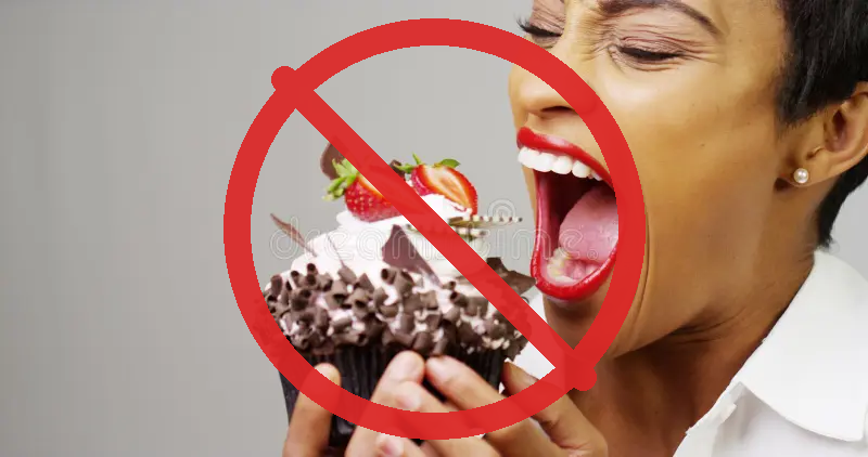 Woman taking a huge bite of a chocolate cupcake with a red prohibition sign overlaid &mdash; no sweets during the Five S&rsquo;s